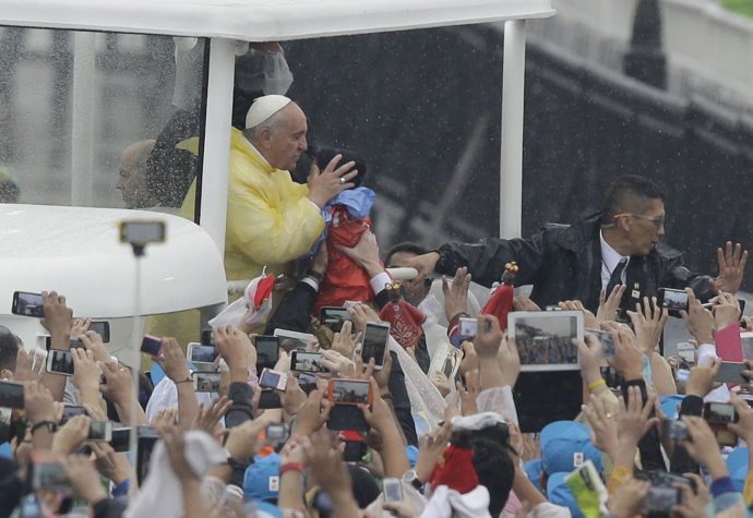 Pápež v silnom daždi bozkáva dieťa. Foto - TASR/AP