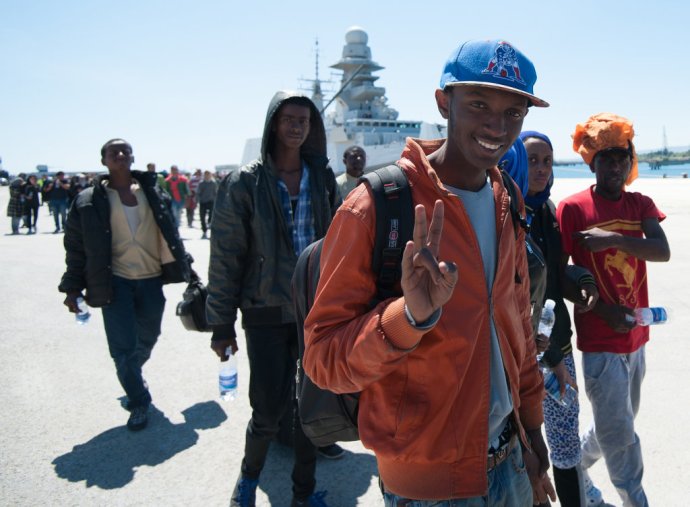 Zachránený africký imigrant ukazuje znak víťazstva po vylodení z talianskeho námorného plavidla Bettica v sicílskom prístave. FOTO - TASR/AP