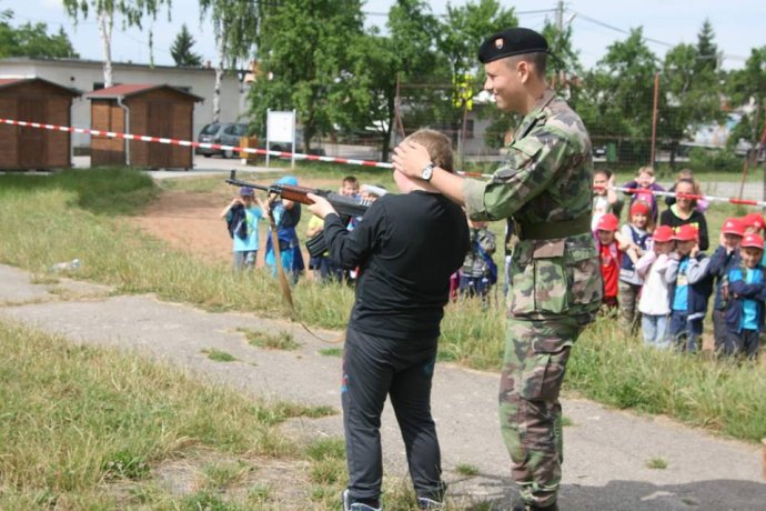 Švrček na fotke z roku 2015 učí deti na základnej škole v Ludaniciach strieľať slepými zo samopalu. Foto – Slovenskí branci
