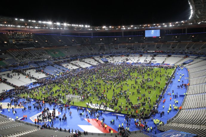 Diváci sa po explóziách v komplexe štadióna Stade de France utiahli na ihrisko, kde ich strážili policajti. Foto – AP