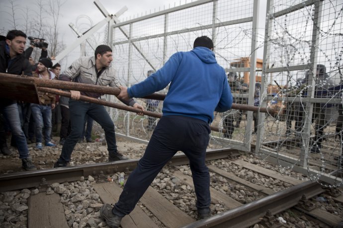 Utečenci v snahe otvoriť si plot do Macedónska. Balkánska krajina prijíma len minimum ľudí. Foto – AP