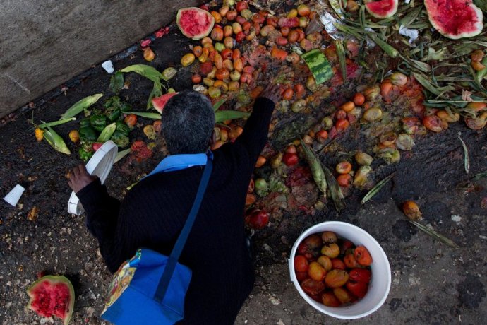 Venezuelčan zbiera vyhodené paradajky na trhu v Caracase. Foto - ap