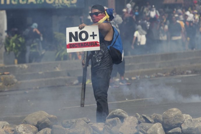 Demonštrant v Caracase s transparentom „Nie diktatúre“. Foto – AP