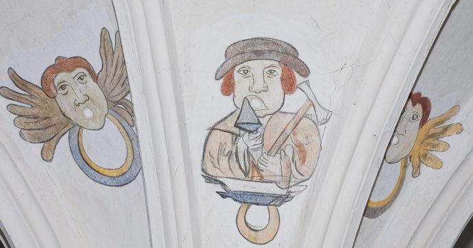 Maľované symboly na neskorogotickej klenbe nad pilierom pri západnej empore v Šamoríne. Medzi nimi je karikovaný portrét staviteľa majstra Petra s murárskou lyžicou a kladivom. Foto - Peter Kresánek