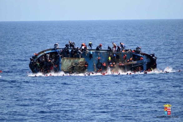 Ľudia vyskakujú z lode po jej prevrátení pri pobreží Líbye 25. mája 2016. Najmenej sedem migrantov zahynulo. Foto – TASR/AP