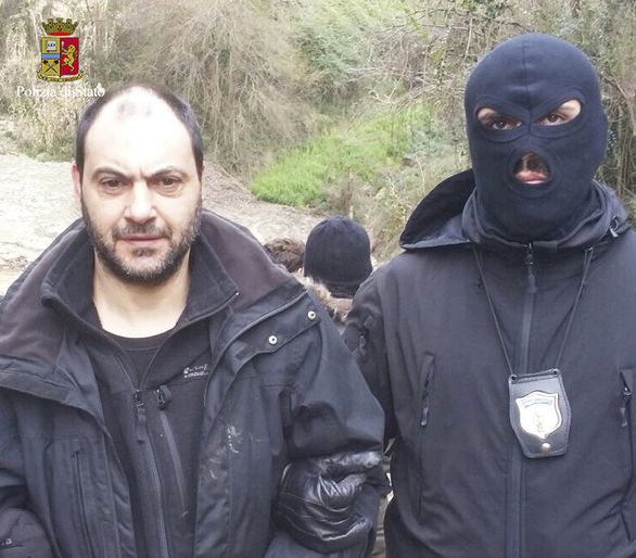 Na snímke kukláč odváža jedného z dvoch popredných členov obávaného talianskeho zločineckého klanu Ndrangheta Giuseppeho Ferrara zatknutého v roku 2016. Foto – TASR/AP