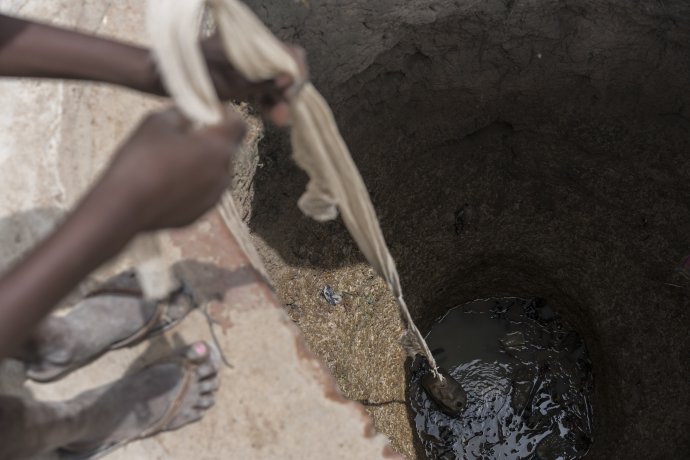 Dieťa naberá špinavú vodu v studni v Južnom Sudáne. Foto - TASR/AP