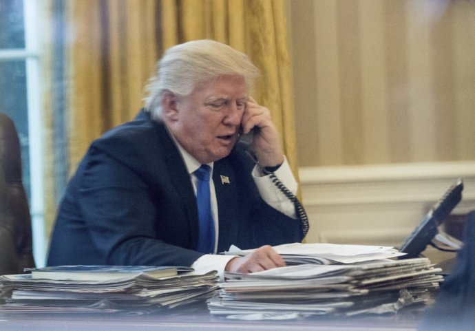 V tomto prípade telefonuje americký prezident Donald Trump s nemeckou kancelárkou Angelou Merkelovou cez pevnú linku v Oválnej pracovni Bieleho domu. Takto by mal podľa svojich bezpečnostných poradcov telefonovať stále. Foto - TASR/AP
