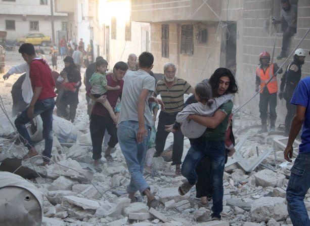 Idlib, Sýria, 29. septembra 2016: Ľudia utekajúci zo sutín zbombardovanej budovy v provincii Idlib, (OMAR HAJ KADOUR/AFP/Getty Images)