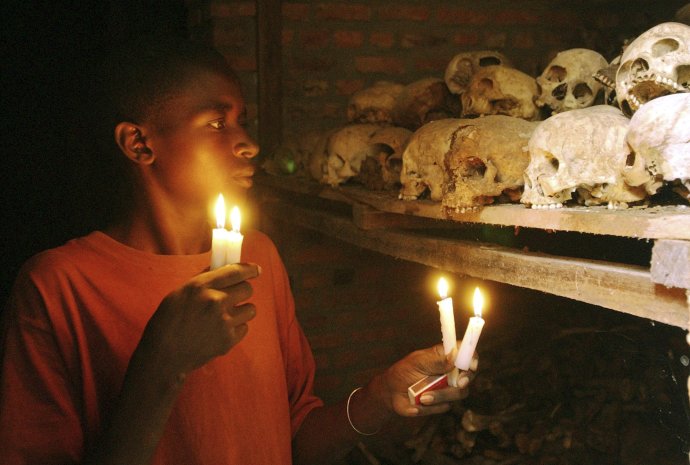 Apollan Odetta, ktorý prežil genocídu v Rwande, drží horiace sviečky v masovom hrobe Nyamate. Foto – TASR/AP