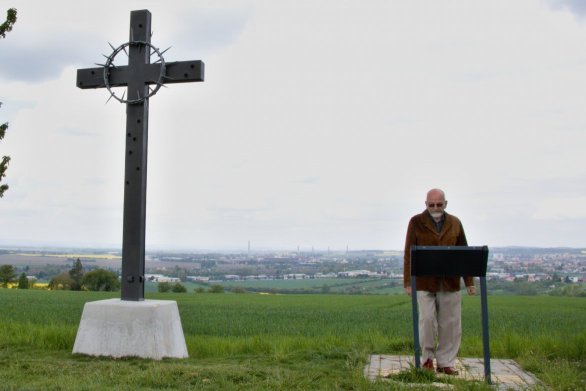 Historik František Hýbl pri kovovom kríži s tŕňovou korunou, ktorý stojí na mieste hromadného hrobu. Foto – Deník N/Karolína Poláčková