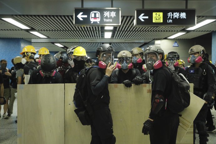 Demonštranti s provizórnymi štítmi prechádzajú stanicou metra cestou na protest v Hongkongu. Foto TASR/AP