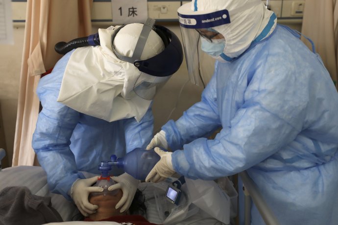 Zdravotníci vo Wu-chane pomáhajú pacientovi s koronavírusom. V ochrannom odeve musia vydržať často až osem hodín. Foto - TASR/AP