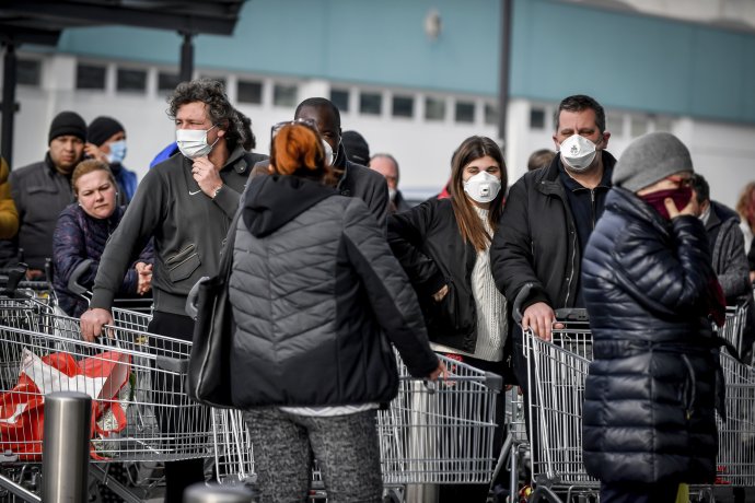 Ľudia s rúškami čakajú pred supermarketom v talianskom Casalpusterlengu. Foto - TASR/AP