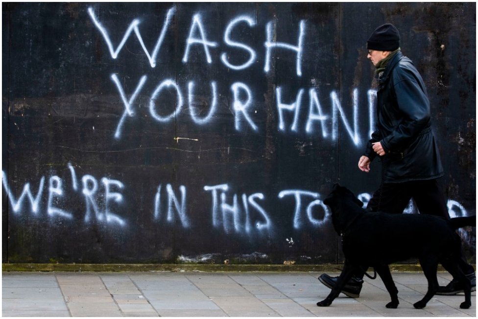 Muž na prechádzke so psom prechádza okolo nápisu „Umývaj si ruky, sme v tom spoločne“ na ulici v severoírskom Belfaste. Foto - TASR/AP
