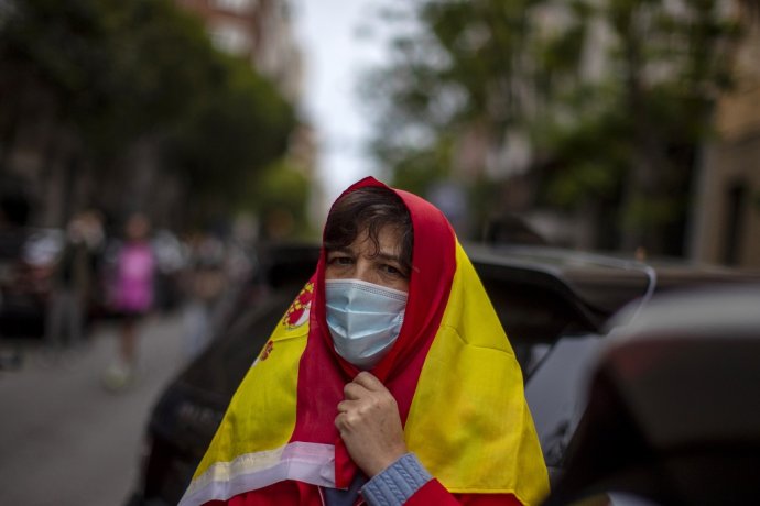 Žena s rúškom a španielskou vlajkou na hlave počas protestov proti tomu, ako vláda zvláda koronakrízu. Ilustračné foto - TASR/AP.