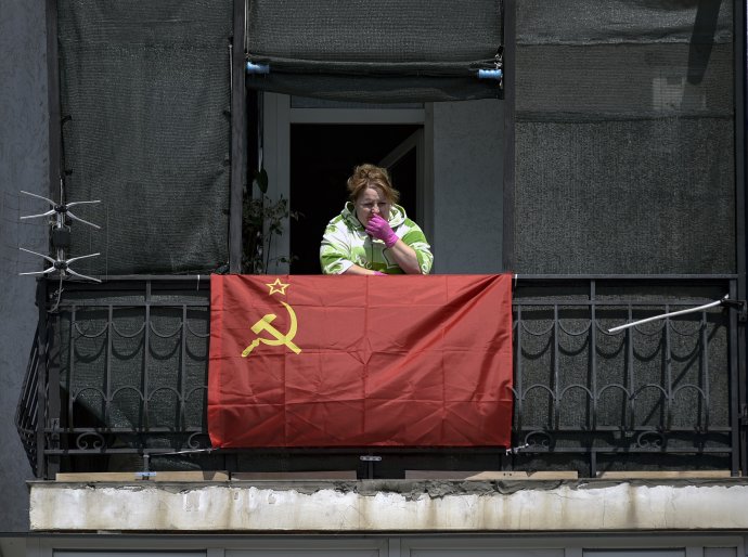 Žena z krymského Sevastopola víta prvý máj v gumených rukaviciach a so sovietskou vlajkou. Foto – TASR/AP