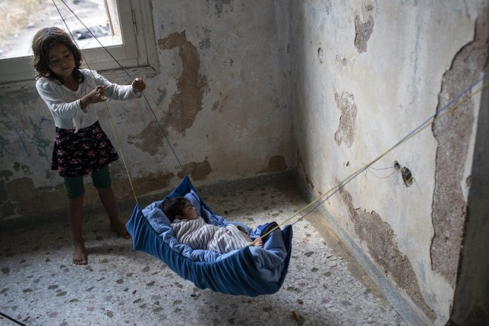 Dievčatko z Afganistanu uspáva dvojmesačné bábätko v gréckom utečeneckom tábore v roku 2020. Foto - TASR/AP