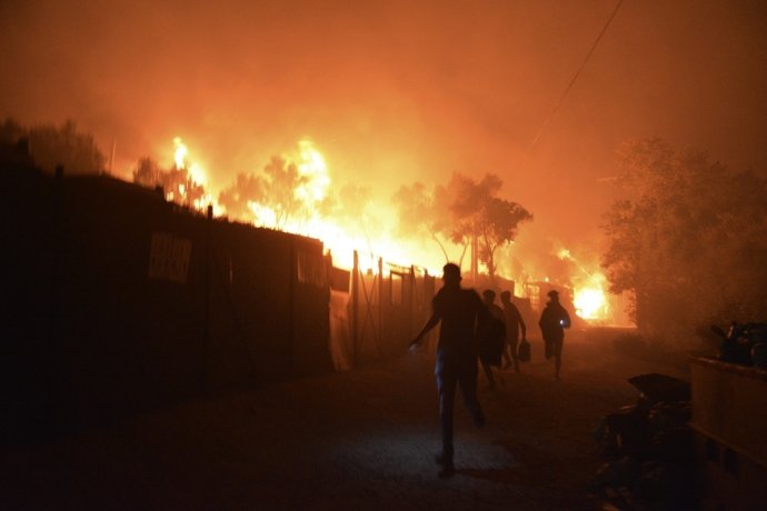 Utečenci a migranti utekajú počas požiaru, ktorý zachvátil preplnený utečenecký tábor Moria na gréckom ostrove Lesbos v stredu 9. septembra 2020. Foto - TASR/AP
