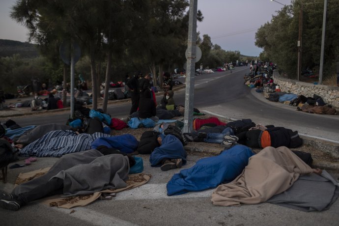 Migranti spia na ceste neďaleko zhoreného utečeneckého tábora Moria na preplnenom gréckom ostrove Lesbos. Foto - TASR/AP