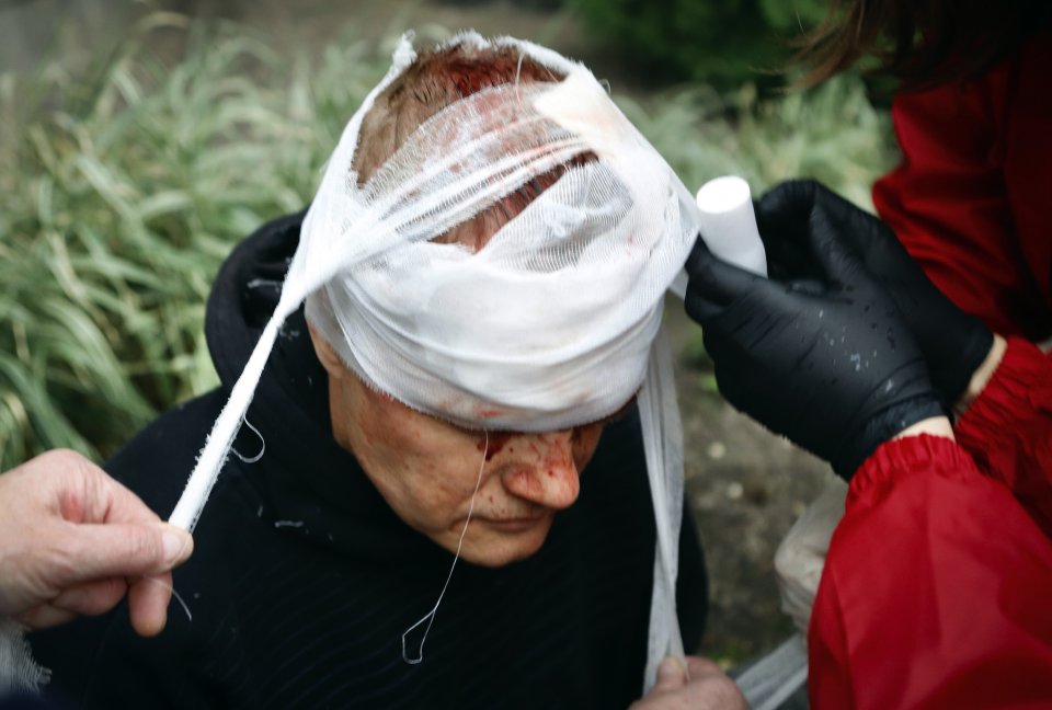 Ľudia ošetrujú zraneného demonštranta počas protestu v Minsku. Foto - TASR/AP