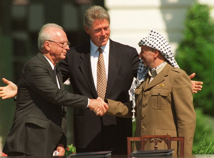 Na archívnej snímke z 13. septembra 1993 si palestínsky prezident Jásir Arafat (vpravo) podáva ruku s izraelským premiérom Jicchakom Rabinom v prítomnosti amerického prezidenta Billa Clintona po podpise mierovej dohody medzi Izraelom a Palestínčanmi vo Washingtone. Foto – TASR/AP
