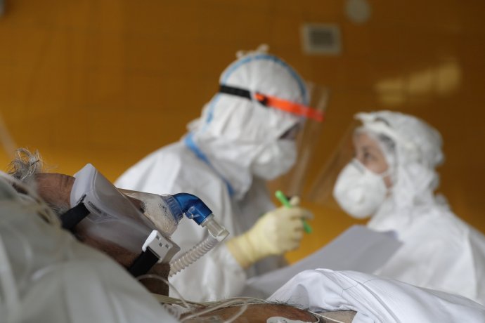 Lekári v špeciálnych ochranných odevoch stoja pri pacientovi s ochorením COVID-19 na jednotke intenzívnej starostlivosti v pražskej Nemocnici na Bulovke. Foto - TASR/AP