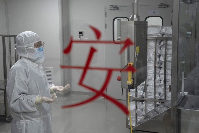 Zamestnankyňa v ochrannom odeve stojí pri nápise „Bezpečnosť“ počas kontroly výroby experimentálnej vakcíny proti novému typu koronavírusu v závode farmaceutickej spoločnosti SinoVac v Pekingu 24. septembra 2020. Foto – TASR/AP