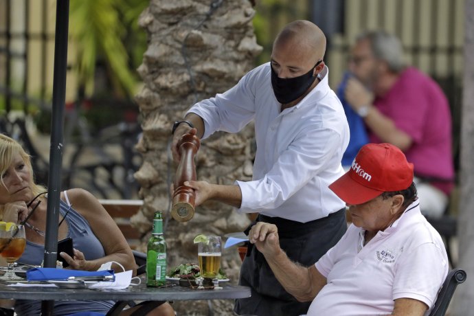 Čašník s rúškom obsluhuje muža v máji 2020 v meste Petersburg na Floride. Foto - tasr/ap