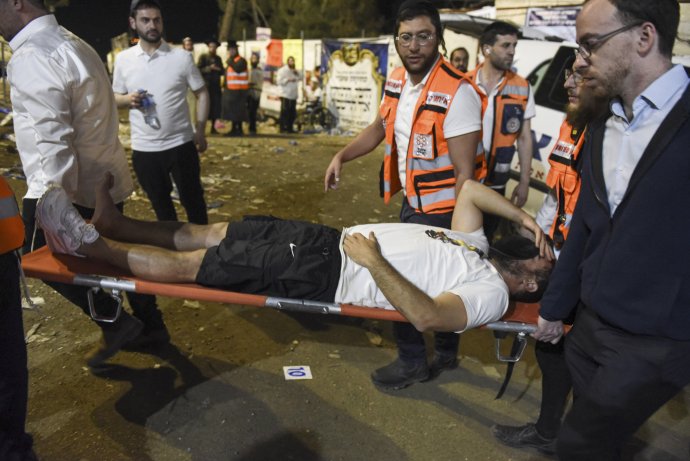Izraelskí záchranari nesú zraneného veriaceho z miesta nešťastia. Foto - TASR/AP