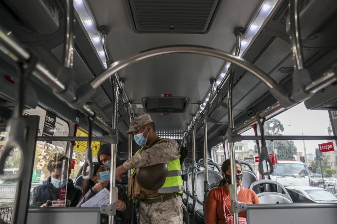 Vojak kontroluje povolenie na pobyt vonku u cestujúcich v autobuse. Foto - TASR/AP