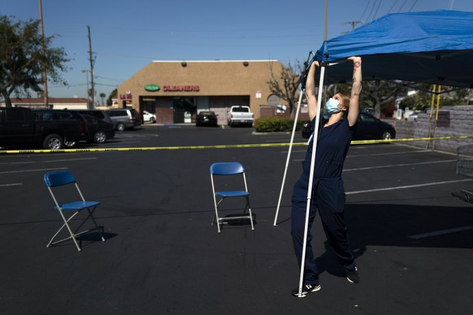 Dobrovoľníčka rozkladá očkovací stan na parkovisku v kalifornskom meste Orange. Ilustračné foto – TASR/AP