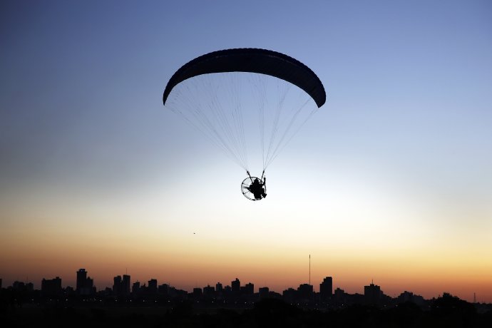 Muž letí v motorovom paraglajde nad Costanerou de Asunción v Paraguaji, obľúbeným miestom kryptotraderov. Foto - TASR/AP