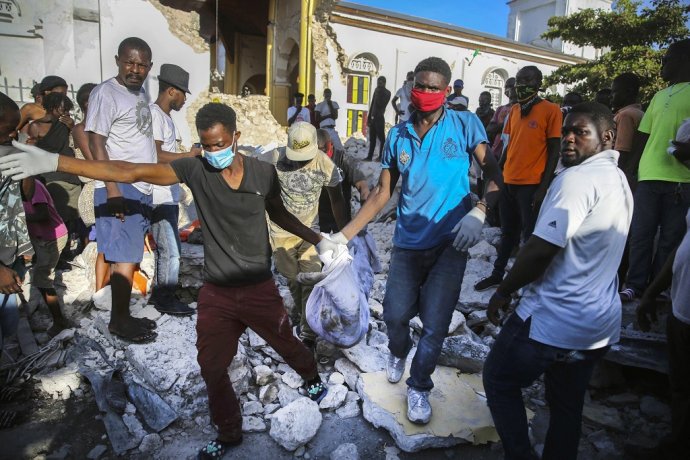 Ľudia vyťahujú mŕtve telo z trosiek po zemetrasení na Haiti v auguste 2021. Foto: TASR/AP