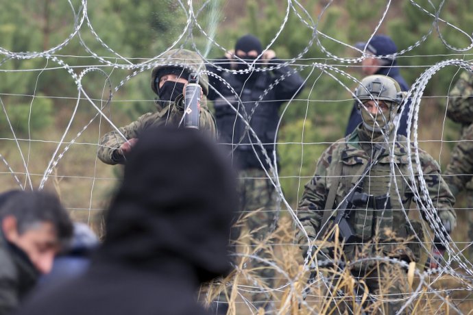 Poľské hraničné stráže za ostatným drôtom, ktorý ich delí od migrantov na bieloruskej strane. Foto - TASR/AP