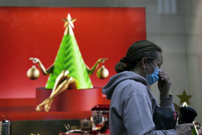 Žena s rúškom na tvári prechádza okolo vianočného výkladu obchodu v Aténach. Obchody sú v Grécku otvorené, aj keď neočkovaných pustia len s testom. Foto - tasr/ap