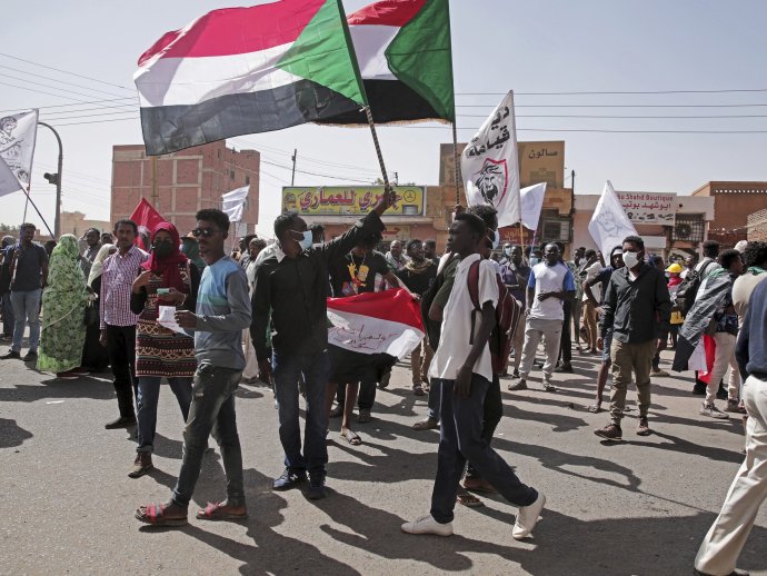 Ľudia držia zástavy počas protestu proti vojenskému prevratu v Chartúme. Slzotvorným plynom zasiahli v pondelok sudánske bezpečnostné sily voči tisíckam demonštrantov, ktorí protestovali proti vlaňajšiemu vojenskému prevratu v krajine a dožadovali sa civilnej vlády. FOTO - TASR/AP