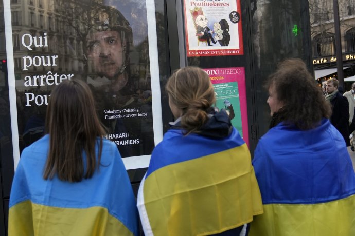 Demonštrantky v ukrajinských vlajkách pri plagáte s Volodymyrom Zelenským na protivojnovom pochode v Paríži 5. marca. Foto – TASR/AP