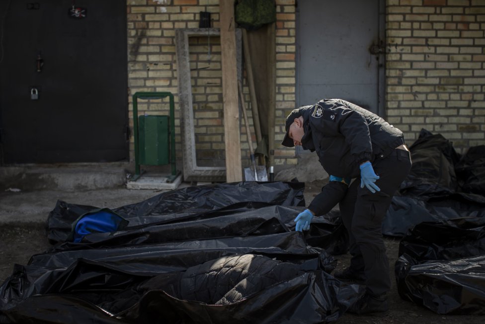 Ukrajinský policajt prezerá mŕtve telo. Foto - Deník N/Gabriel Kuchta