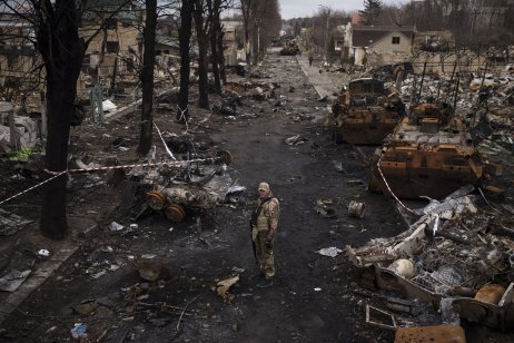 Ukrajinský vojak stojí na ceste plnej zničených ruských tankov v Buči na okraji Kyjiva. Foto – TASR/AP