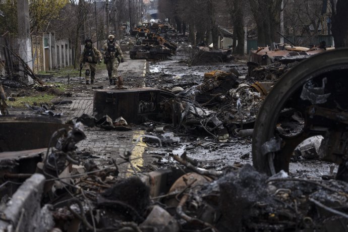 Ukrajinskí vojaci kráčajú popri zničenej ruskej kolóne v oslobodenej Buči západne od Kyjiva. Foto - TASR/AP