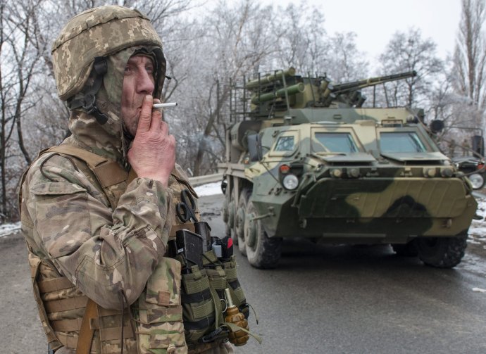 Ukrajinský vojak fajčí pri obrnenom vozidle BTR-4 ukrajinskej výroby. Aj na opravy tejto techniky si slovenský štátny podnik trúfa. Foto - TASR/AP