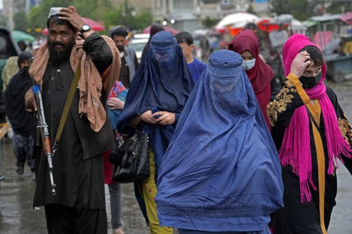 Afganské ženy na trhu kompletne zahalené v modrej afganskej burke sprevádza bojovník Talibanu. Foto - TASR/AP