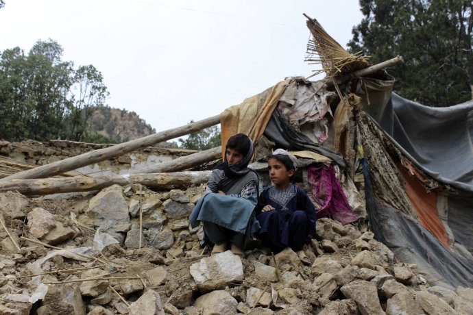 Afganskí chlapci sedia pri zničenom dome po zemetrasení v provincii Khóst. Foto - TASR/AP