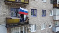 Proruský obyvateľ ukrajinského Lysyčanska s ruskou vlajkou na balkóne svojho bytu po ústupe ukrajinských vojakov. Foto - TASR/AP