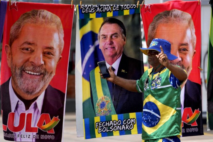 Bolsonarov fanúšik oblečený vo farbách brazílskej vlajky pred obchodom, v ktorom predávajú aj uteráky s prezidentskými kandidátmi. Foto - TASR/AP