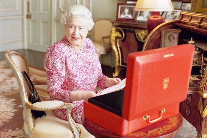 Kráľovná sedí na kresle vo svojej súkromnej audienčnej miestnosti v Buckinghamskom paláci vedľa jedného z oficiálnych červených boxov, v ktorých každý deň dostáva dôležité dokumenty. Foto - TASR /AP