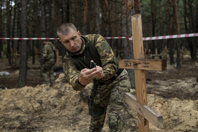 Oleg Kotenko, komisár pre otázky osôb nezvestných za zvláštnych okolností, fotí svojím smartfónom neidentifikované hroby civilistov a ukrajinských vojakov v Iziume. Foto - TASR/AP