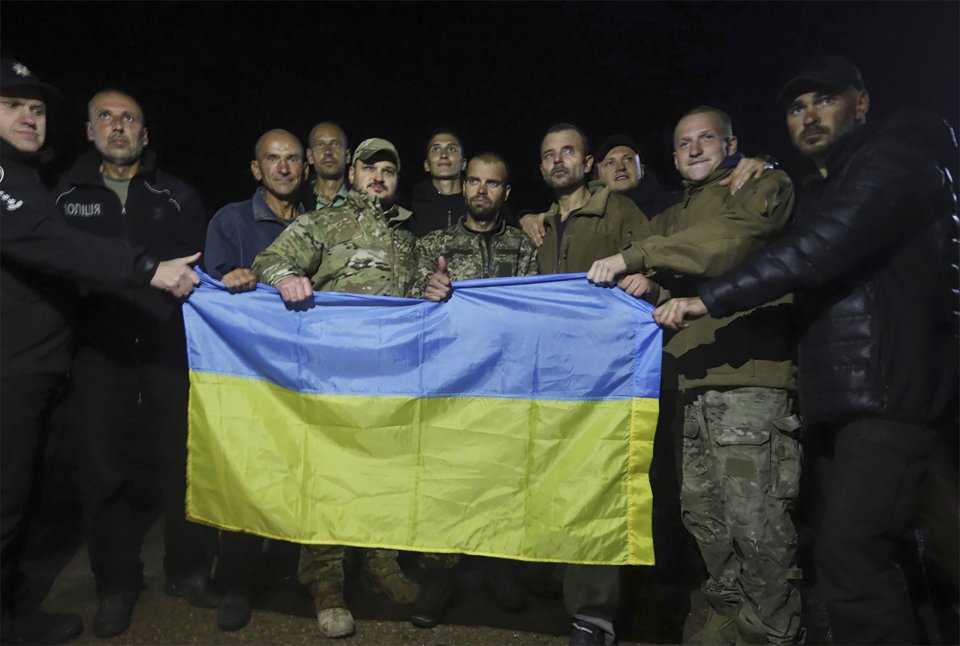Ukrajinskí vojaci s vlajkou po tom, čo ich Rusko prepustilo v rámci výmeny vojnových zajatcov. Foto - Ukrainian Security Service Press Office, TASR/AP