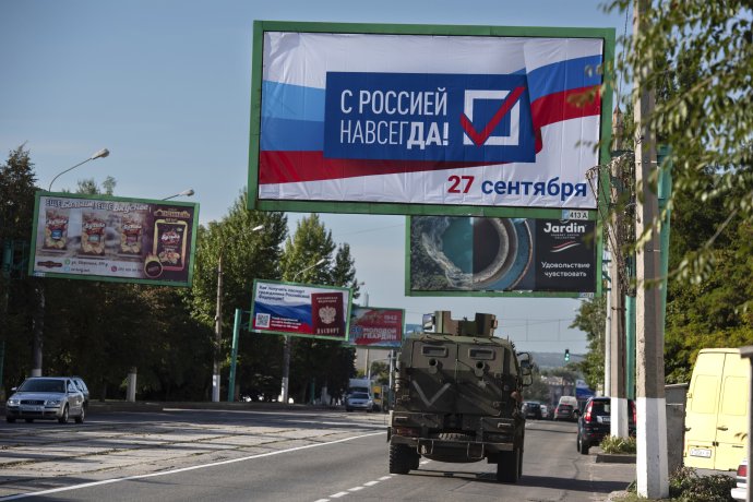 Vojenské vozidlo prechádza okolo bilbordu s nápisom "Navždy s Ruskom, 27. september" v čase referenda v ukrajinskom Luhansku kontrolovanom proruskými separatistami. Foto - TASR/AP